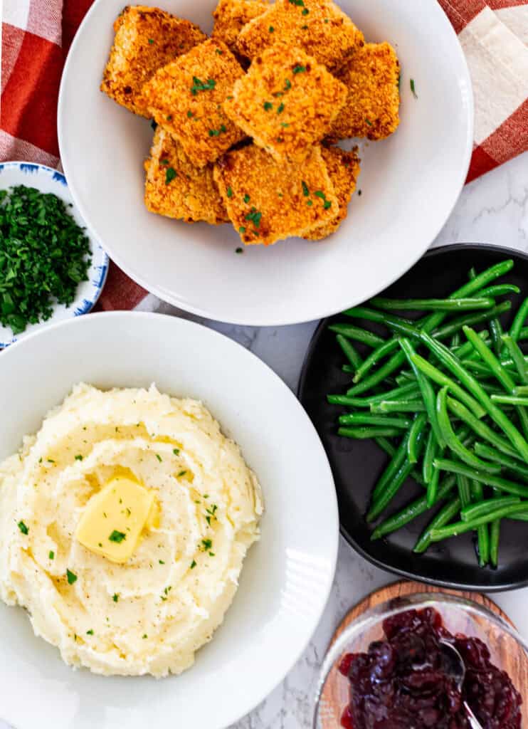 Overhead view of mashed potatoes, mac and cheese bites, green beans, and cranberry sauce