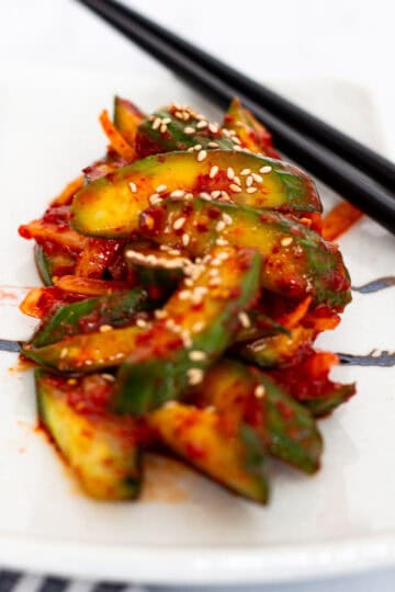Close-up of spicy Korean cucumber salad with sesame seeds served on a plate.