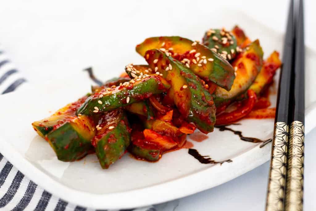 Korean cucumber salad served on a rectangular plate with chopsticks beside it.