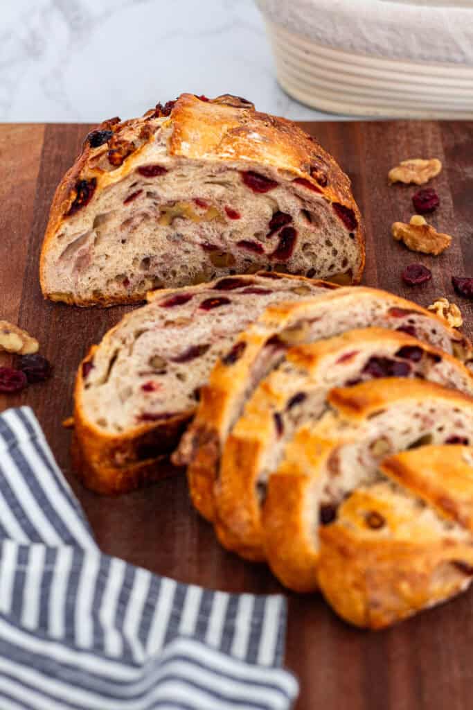 Slices of cranberry walnut bread on a wooden board showing plenty of cranberries and walnuts in each slice