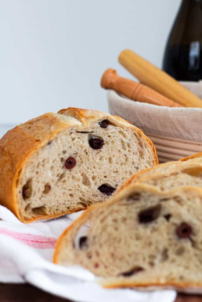 Close-up of a sliced olive sourdough loaf with an airy crumb and baked-in olives.