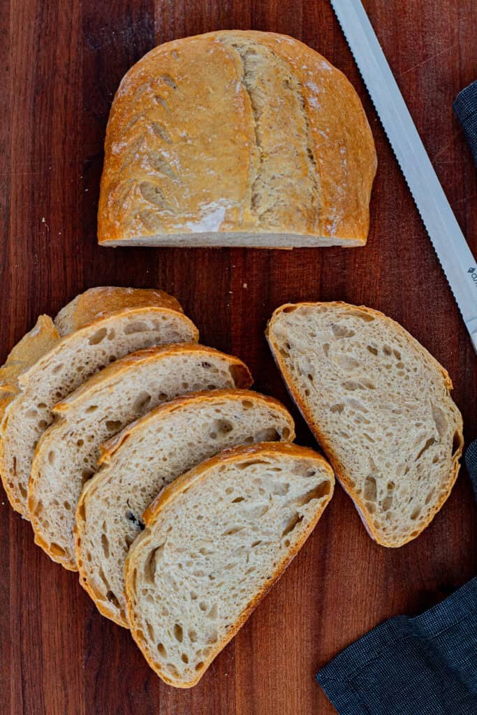 Half loaf of sourdough discard bread with several slices arranged on a wooden board.