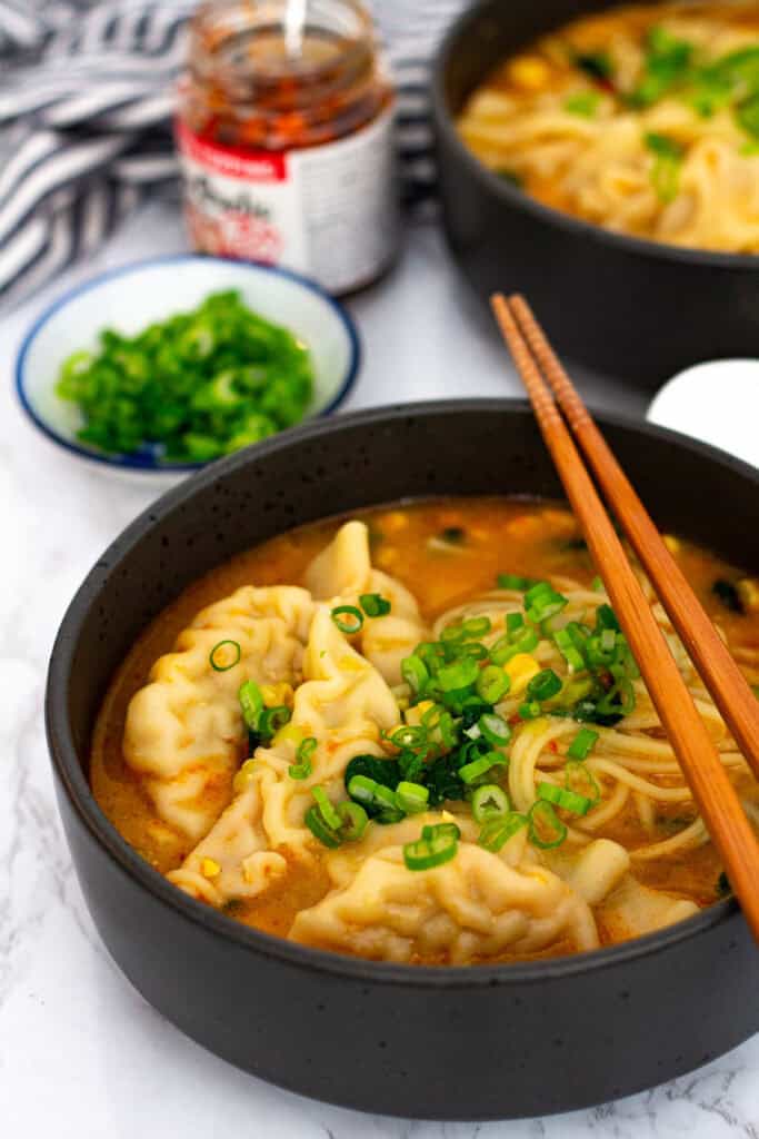 Finished dumpling noodle soup with noodles, dumplings, spinach, and corn in a spicy miso broth.