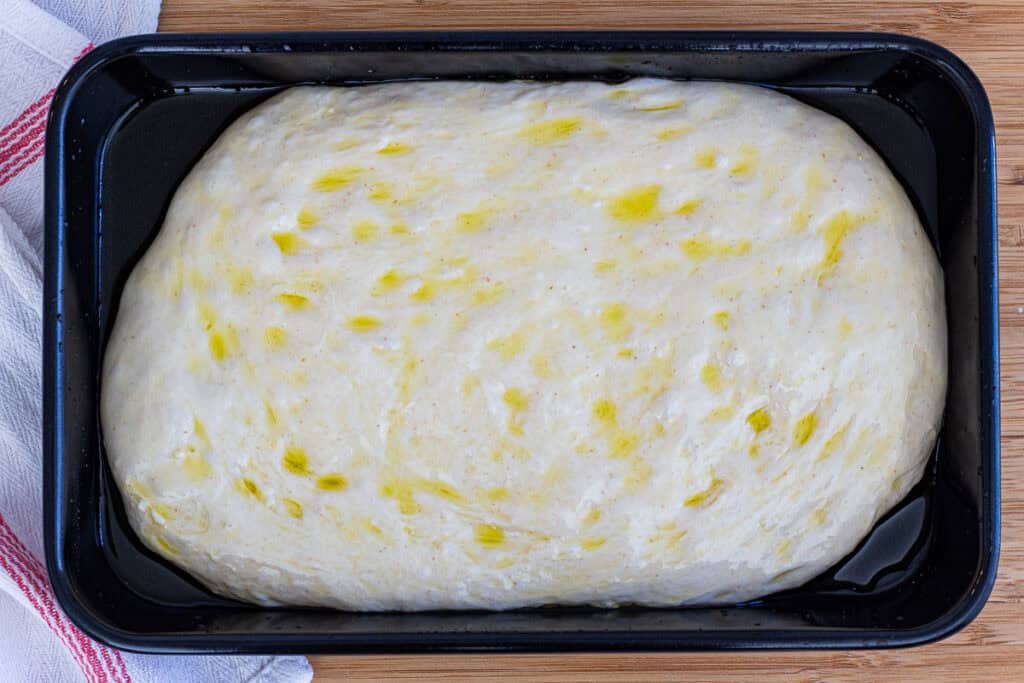 Sourdough discard focaccia dough transferred to olive oil–coated baking pan