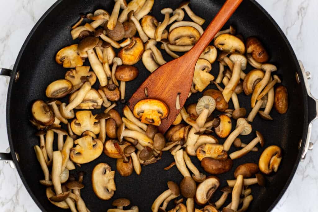 Mixed mushrooms browning in a wide skillet to build flavor for miso mushroom pasta