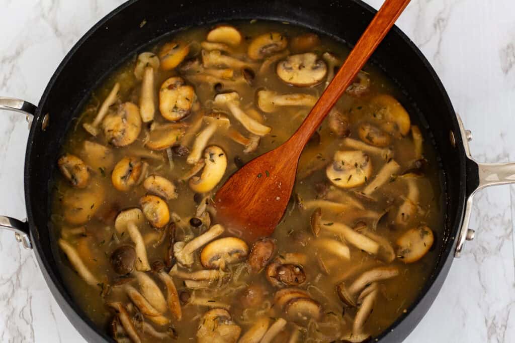 Vegetable broth added to mushrooms to create a glossy sauce for miso mushroom pasta