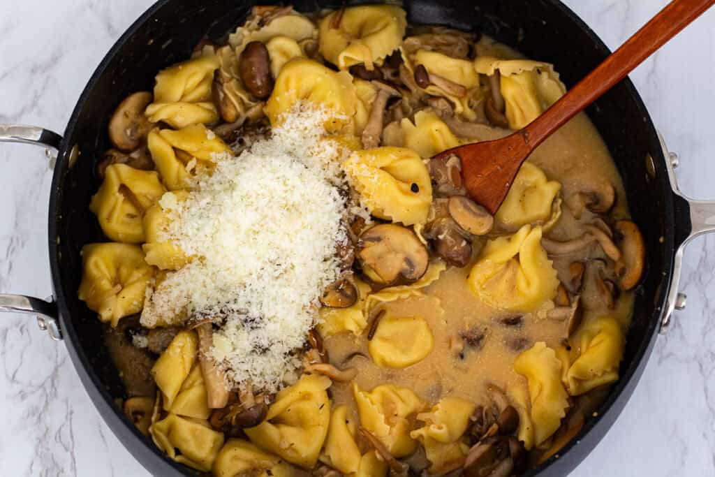 Grated cheese and loosen miso stirred into miso mushroom pasta to finish the creamy sauce