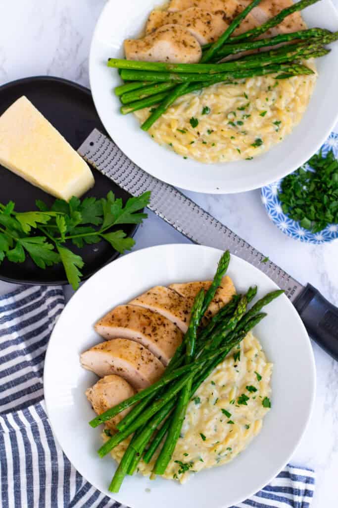 Creamy parmesan orzo served with sliced chicken breast and roasted asparagus for a cozy dinner