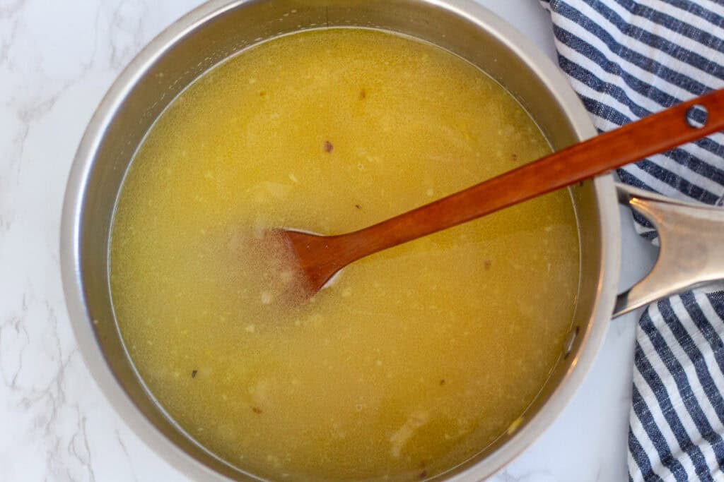 Orzo simmering in chicken broth in a saucepan as it cooks until tender
