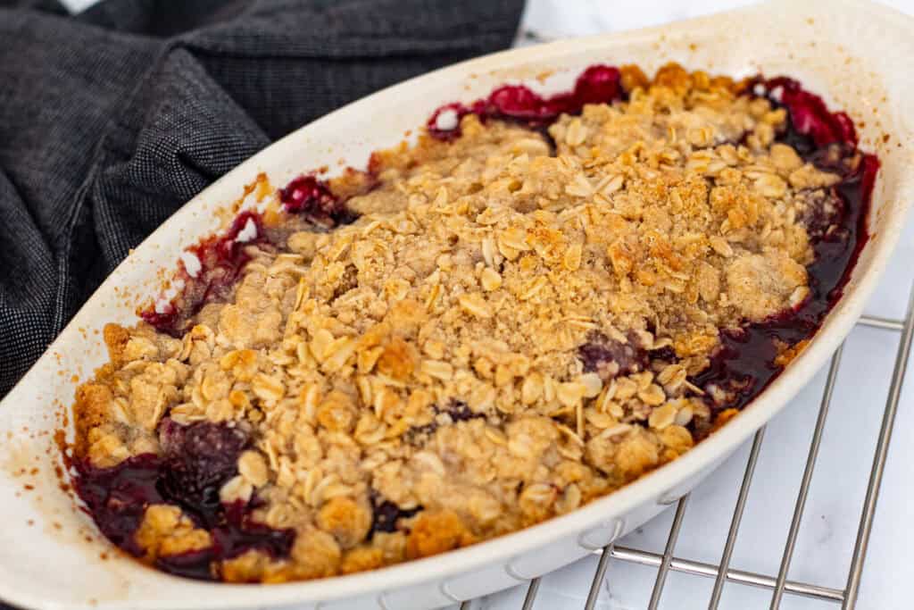 Freshly baked cherry crisp cooling on a rack with golden oat topping and bubbling filling
