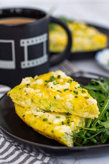 Slice of leek frittata with Boursin served on a plate with fresh chives and coffee.