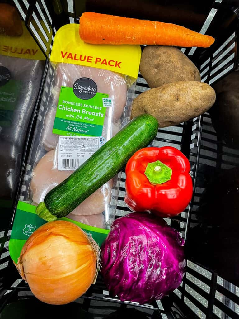 Grocery basket with chicken breast, fresh vegetables, and staples showing how to grocery shop for two and avoid food waste