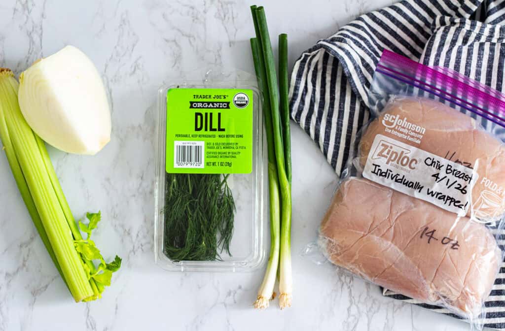 Fresh ingredients organized for the 48 hour rule including onion and celery for immediate use, herbs for later meals, and chicken breast portioned for freezing