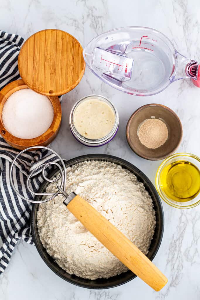 Ingredients for sourdough discard pizza dough including flour, discard, yeast, salt, and olive oil