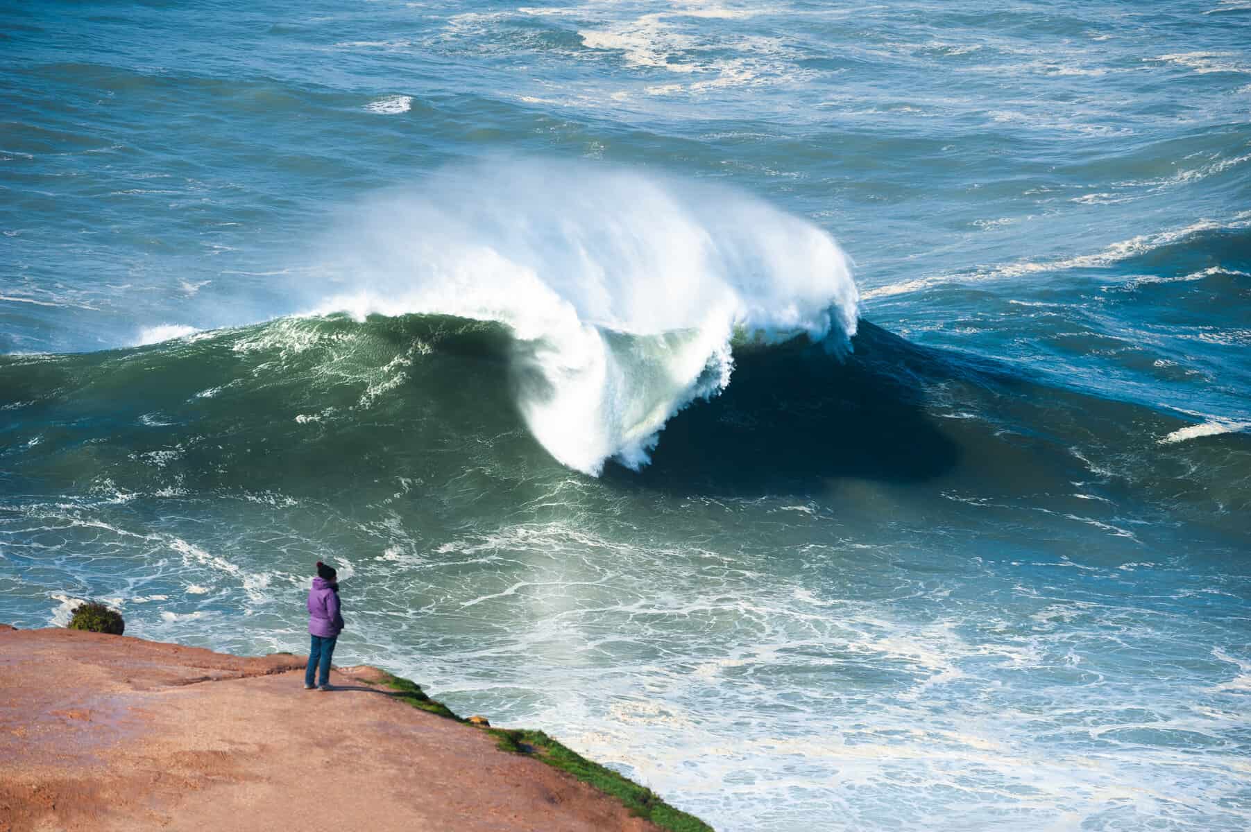Tourist watching big waves in Nazare, Portugal. Season of big waves lasts here from November to March