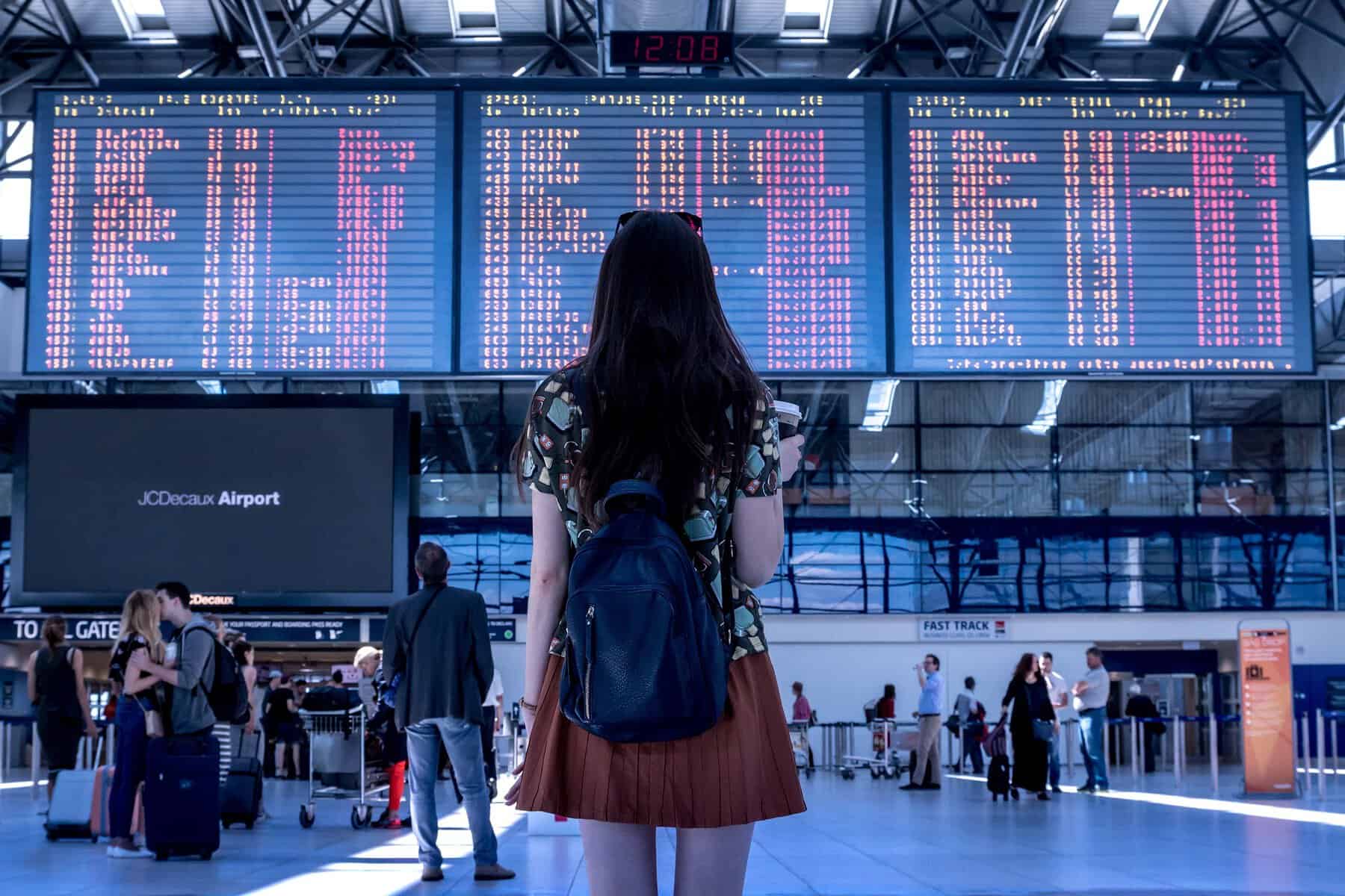 WOMAN LOOKING AT FLIGHT BOARD