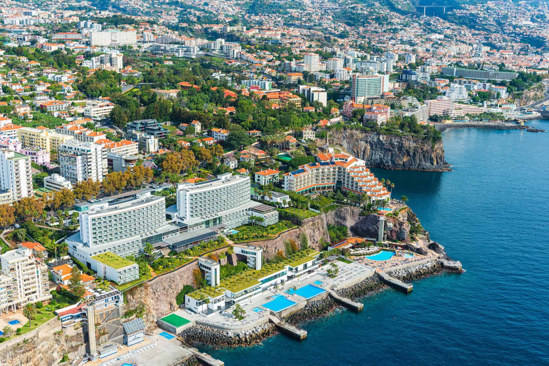 Aerial photography of Funchal, the coastal capital of Madeira. A stunning birds-eye view reveals a bustling cityscape, full of buildings and residential districts with no people in sight.
