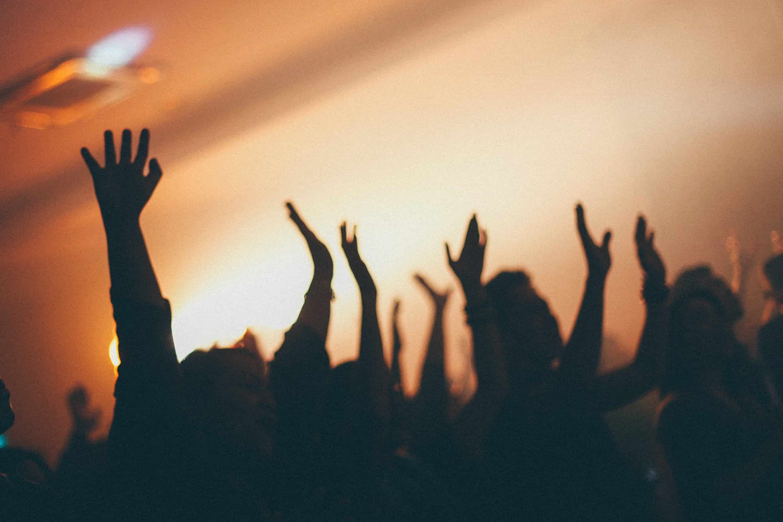 People raising hands in worship at NLW International conference.