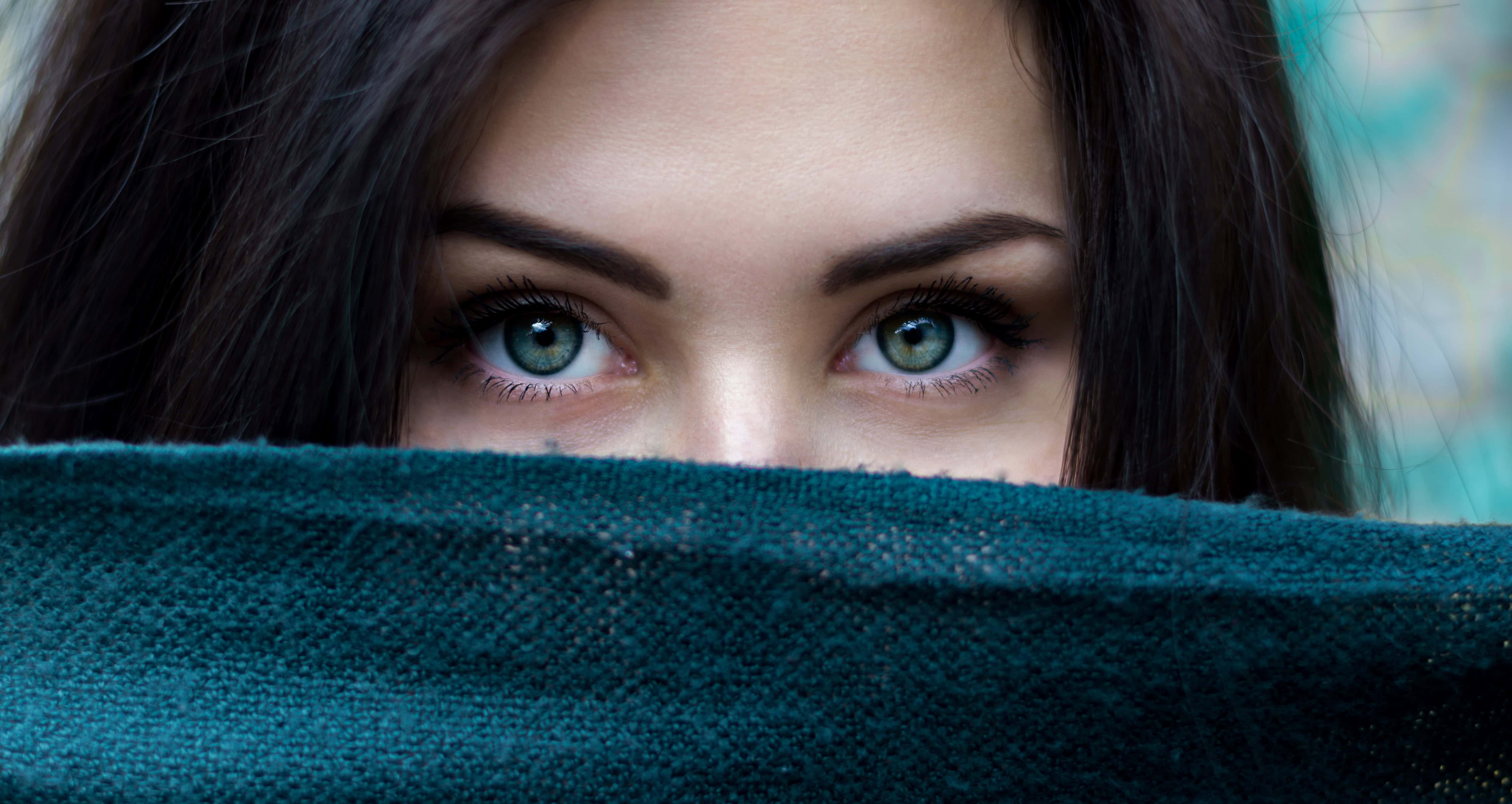Close-up of a woman with striking blue eyes, partially covered face, symbolizing worship and spiritu.
