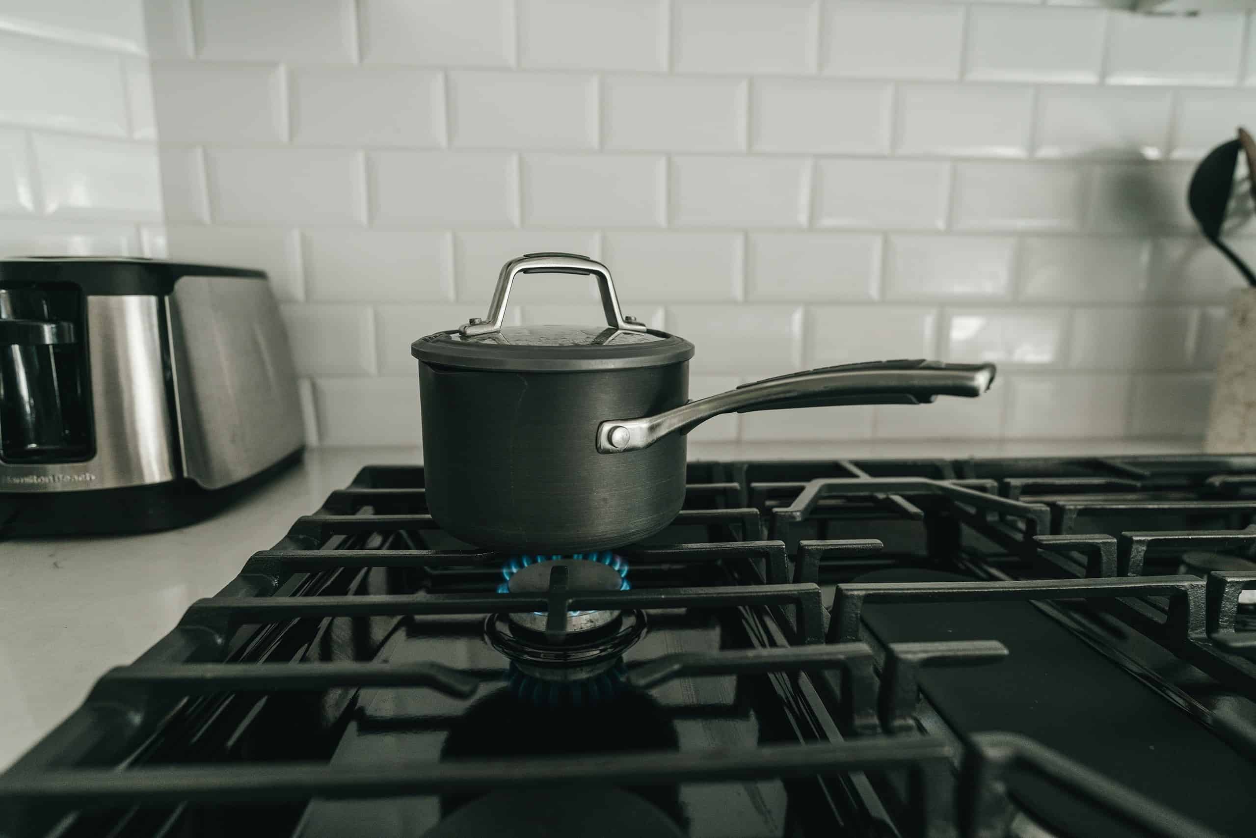 Small black cooking pot on a gas stove burner in a modern kitchen.