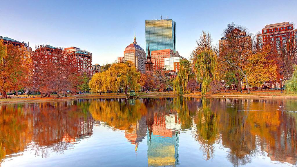 Boston skyline with autumn trees reflected in the Charles River.