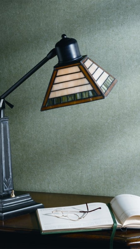 Vintage stained glass desk lamp with a green textured wall background.