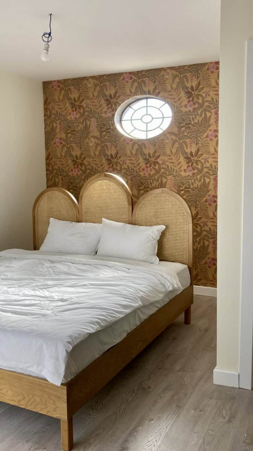 Elegant bedroom with floral wallpaper and unique window design.