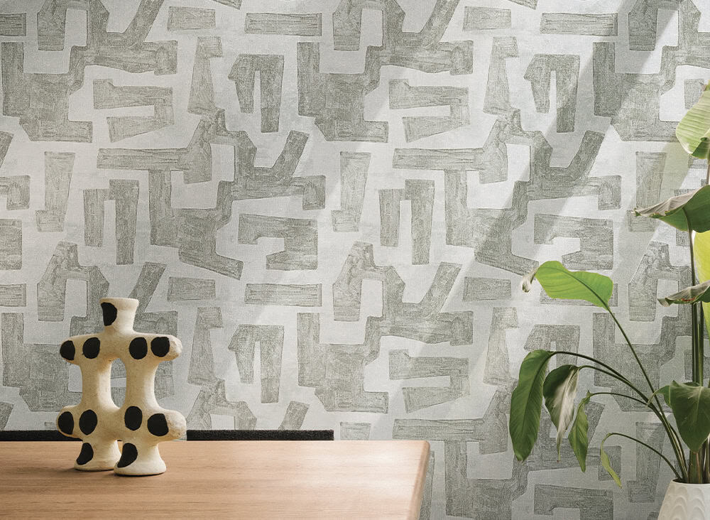 Elegant geometric patterned wallpaper in neutral tones with a decorative ceramic sculpture and green.