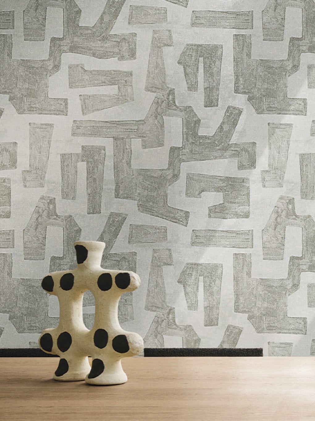 Modern abstract ceramic sculpture with black dots on a light background.