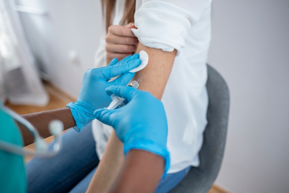 Close-up of a healthcare worker wearing nitrile gloves administering an injection.
