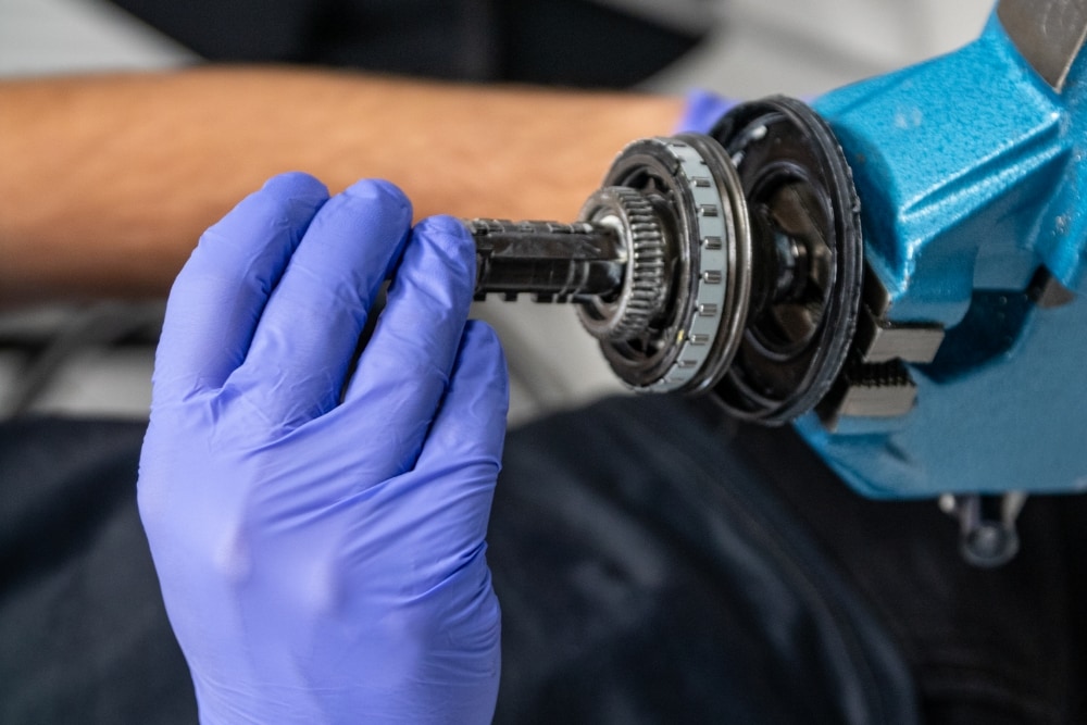 Close-up of gloved hands repairing a mechanical part.