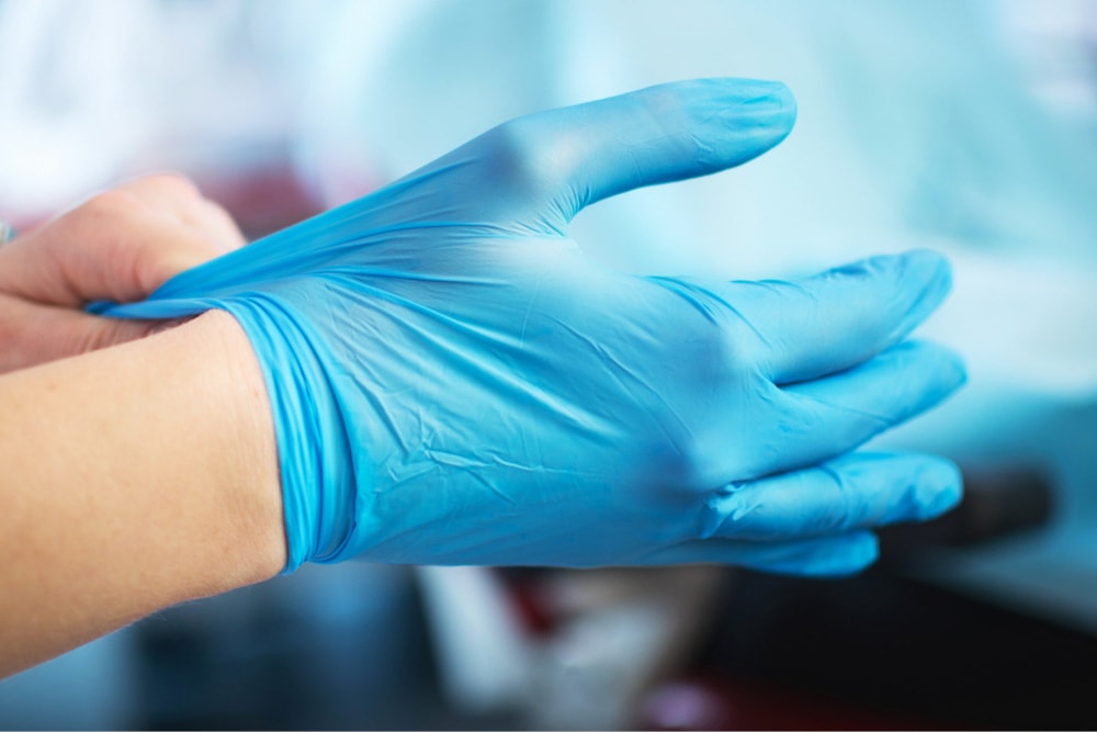 Close-up of hands putting on blue nitrile gloves.