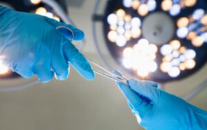 Surgeons' gloved hands exchange surgical scissors in an operating room.