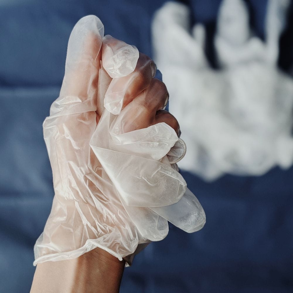 Close-up of hands wearing vinyl gloves, demonstrating food safety practices.