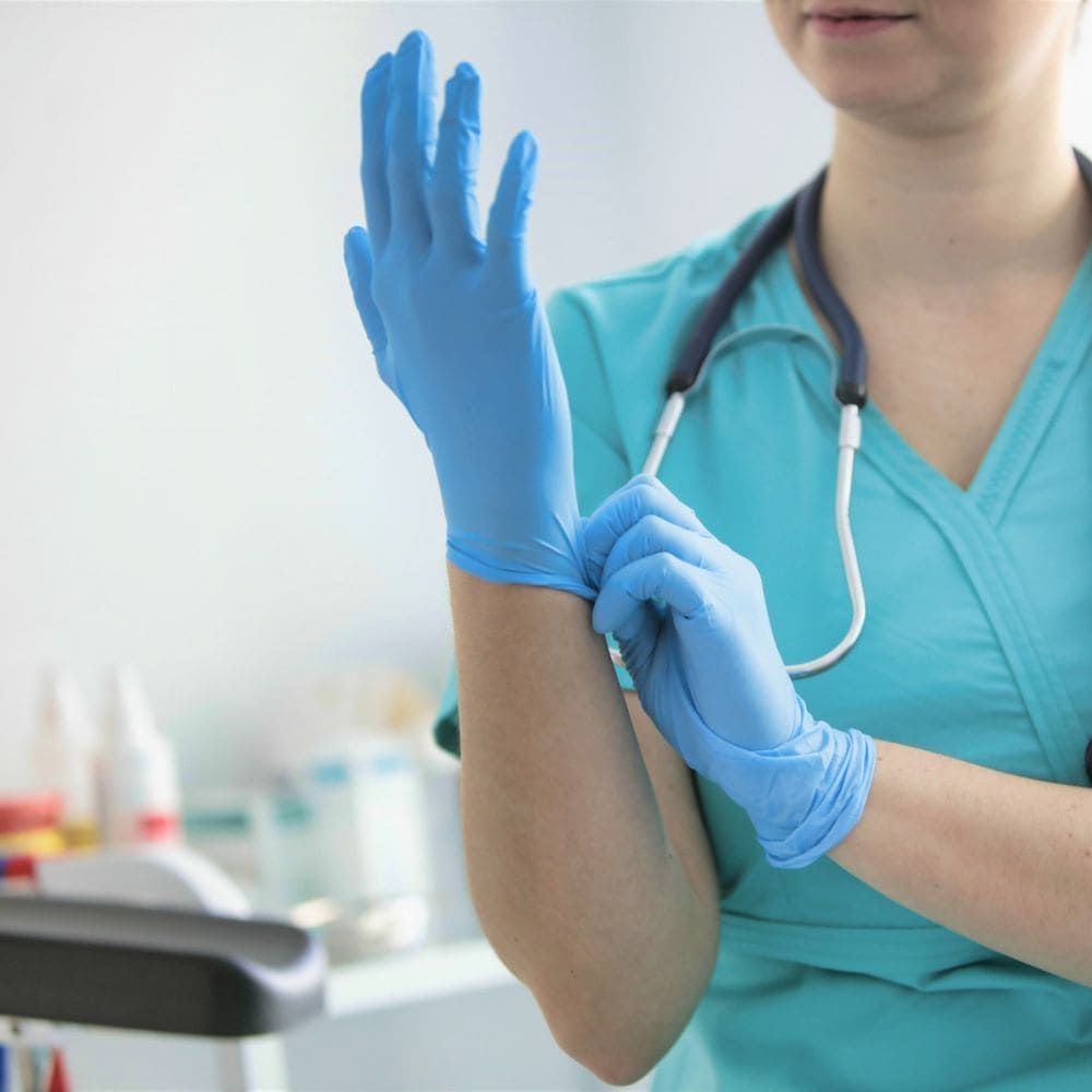 Nurse putting on blue nitrile exam gloves.