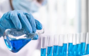 Scientist pouring blue liquid into test tubes. Laboratory research.