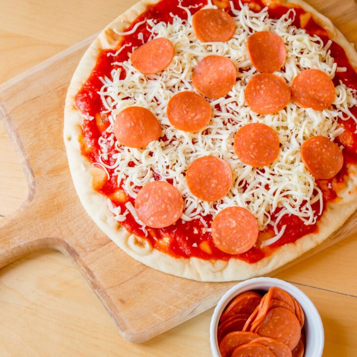 Master the Art of Pizza: Simple Steps to Perfect Easy Pizza Dough | The Not so Modern Housewife homemade pizza with pepperoni and cheese on a pizza peel