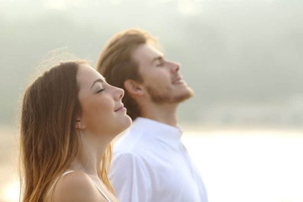 Relaxed couple enjoying outdoor sunshine, promoting mental wellness and stress relief.