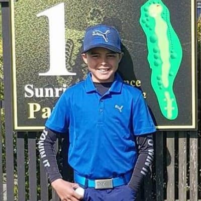 Young golfer in blue sportswear smiling at Sunraysia Golf Course, New Plymouth.