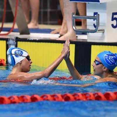 High school swimmers celebrating at the finish line after an aquatic race in the pool.