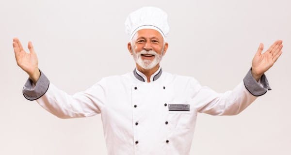 Chef happy lamb partnership Showing happy chef in uniform smiling with raised arms after lamb supplier success