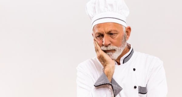 Tired chef poor meat supply Showing a tired chef in uniform holding his face in frustration over meat supply