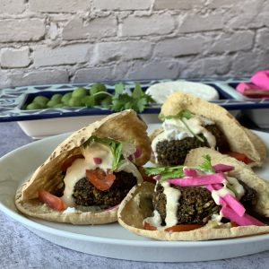 Falafel patties in a pita bread and topped with pink turnip pickles.
