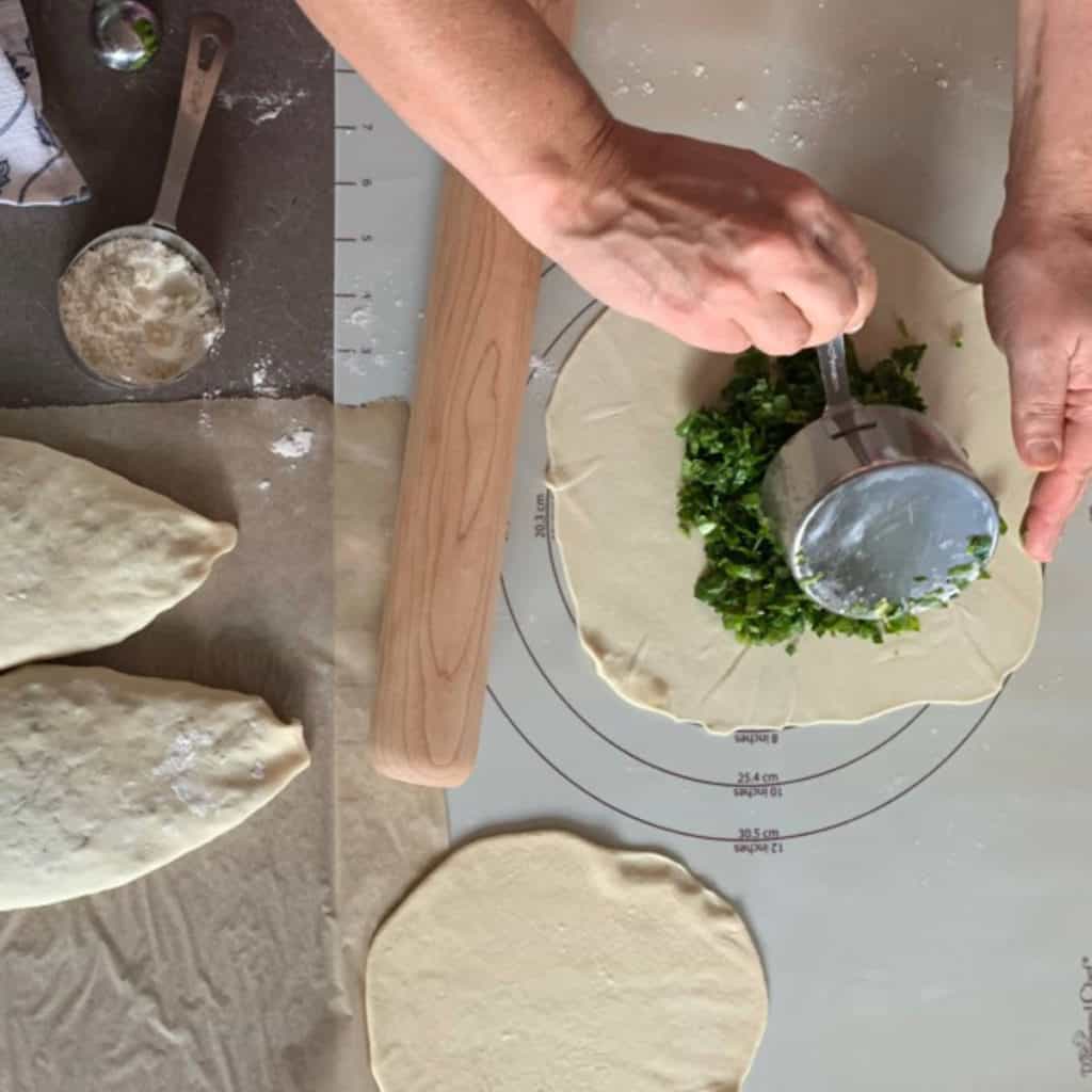 Adding a cupful of greens to the dough.