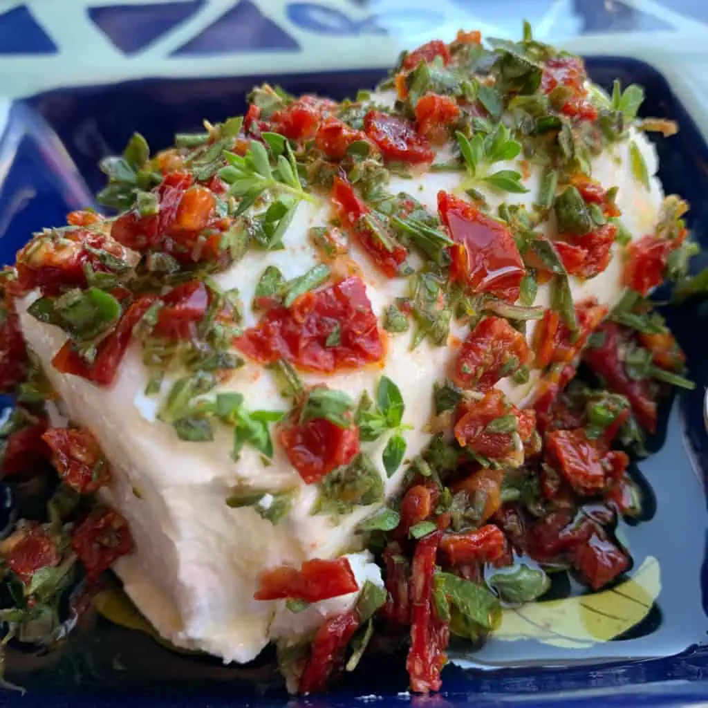 Goat cheese with herb marinate in a blue dish.