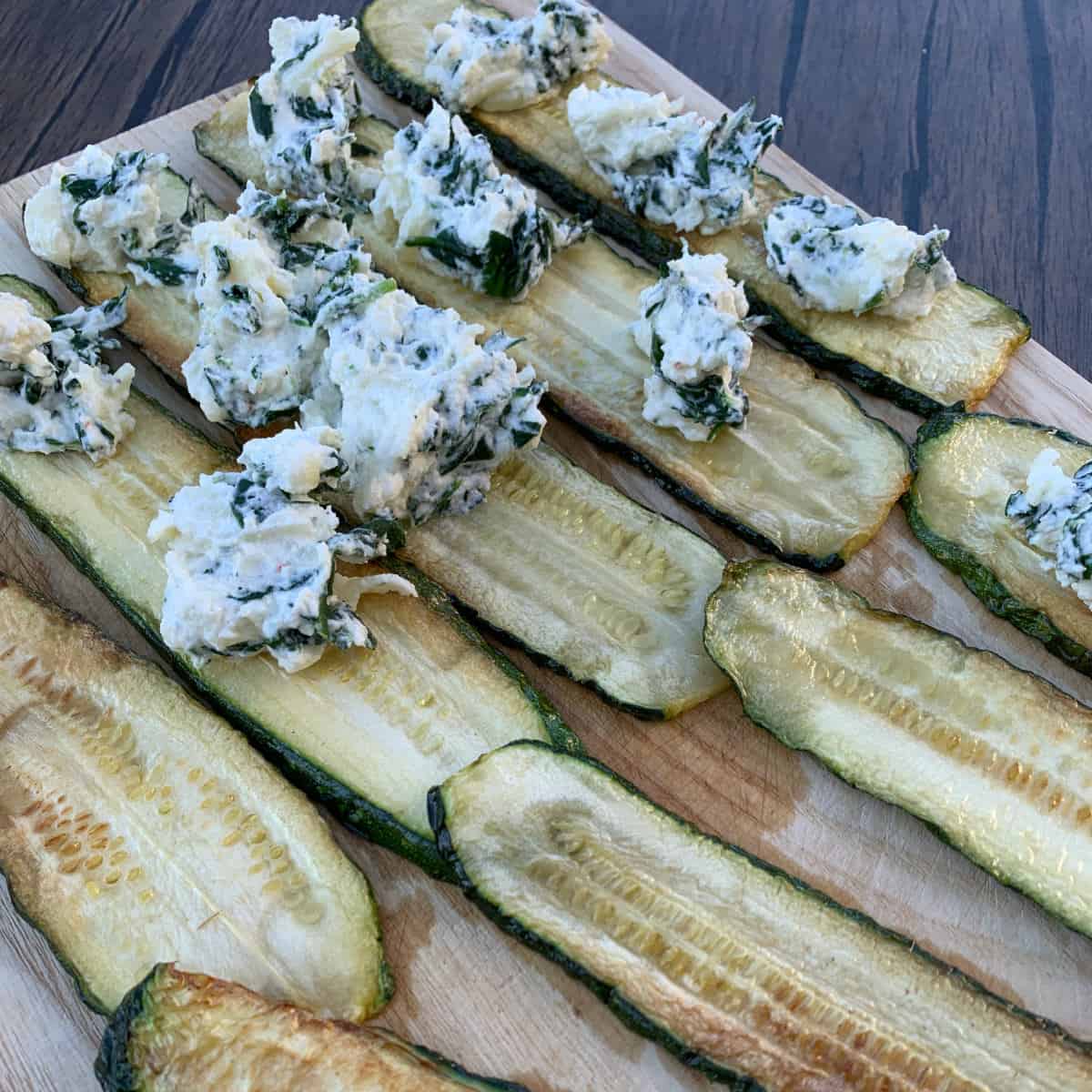 Placing dollop of spread on each zucchini slice.