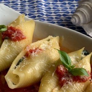 Stuffed Shells in a baking dish and the seashell in the background.