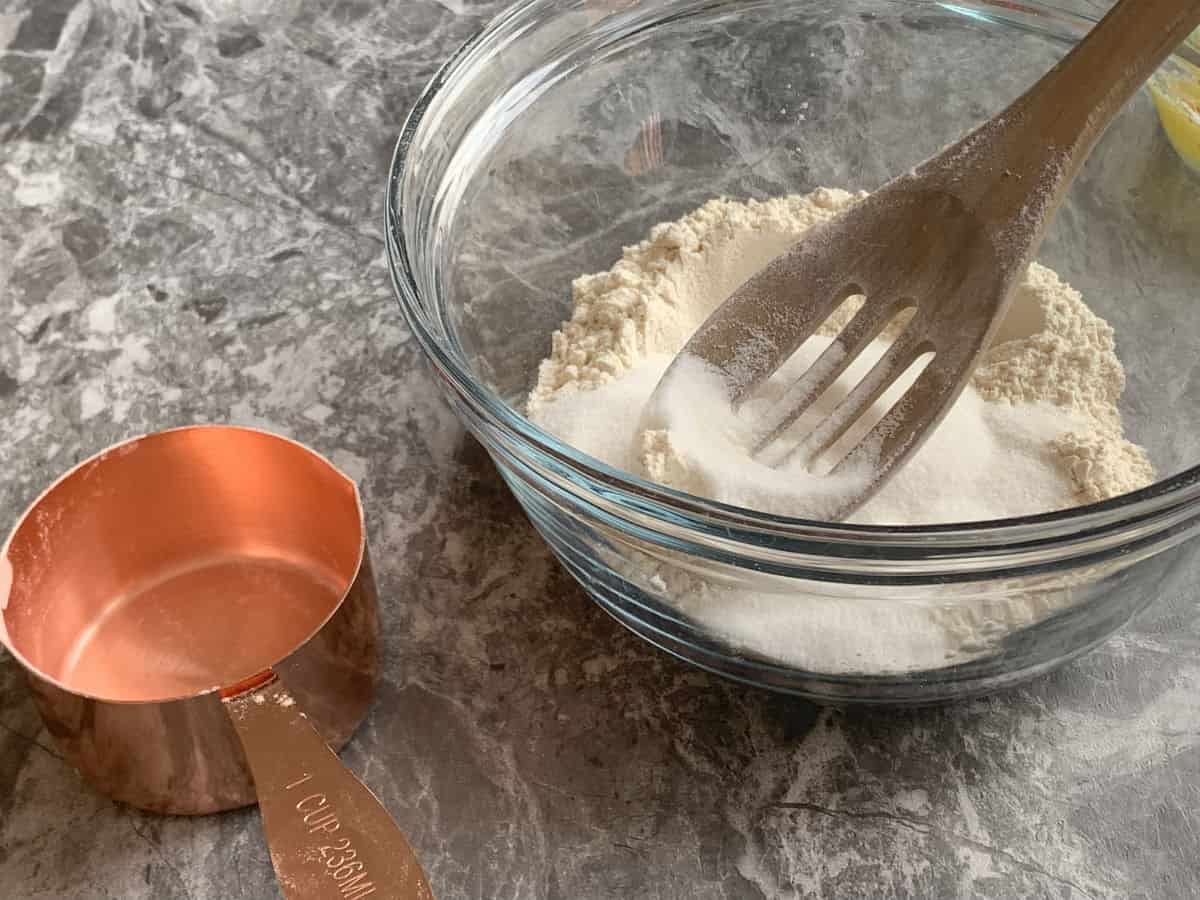 Mixing sugar and flour together in a glass bowl.