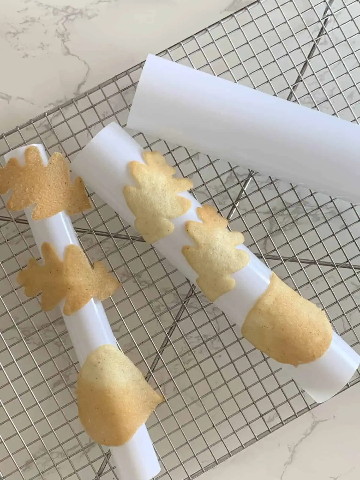 Baked tuile cookies on half pipe.