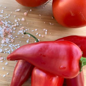 Fresno Peppers and tomatoes on a cutting board.